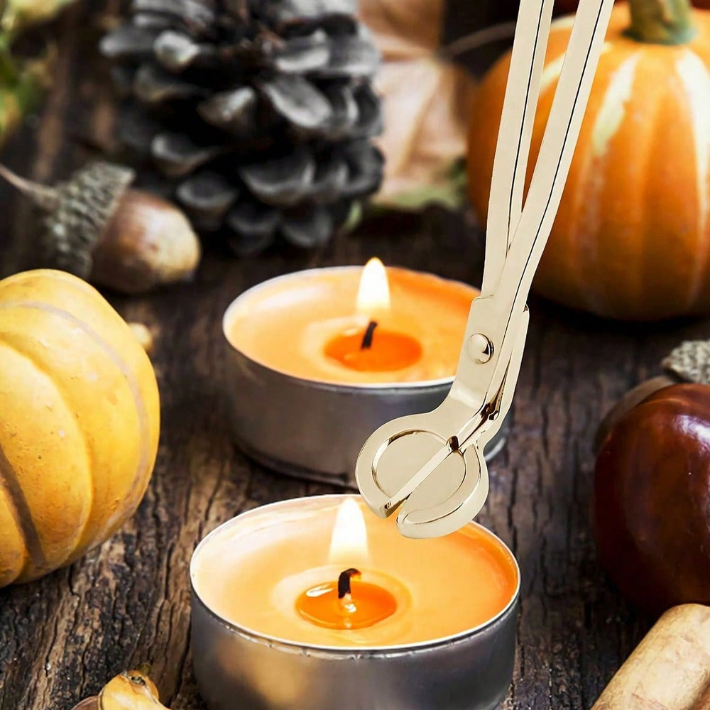 Gold candle care set: wick trimmer cutting the wick of a lit candle