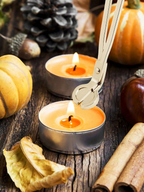 Wick trimmer cutting the wick of a lit candle among autumn pumpkins and cinnamon