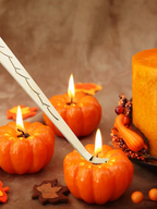 Wick dipper beside lit candles and pumpkins