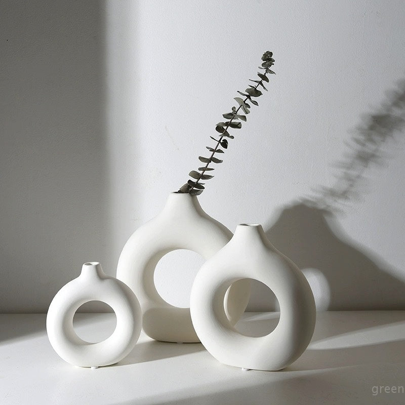 Two matte white donut vases with an eucalyptus stem