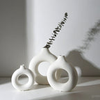 Two matte white donut vases with an eucalyptus stem