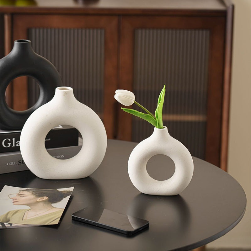 White donut vases on a dark table with a tulip
