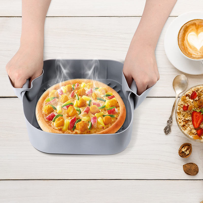 Silicone air fryer tray lifted out with a pizza and pinch-grip mitts